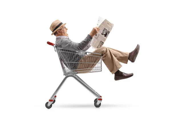 Man with a newspaper riding inside a shopping cart — Stock Photo, Image