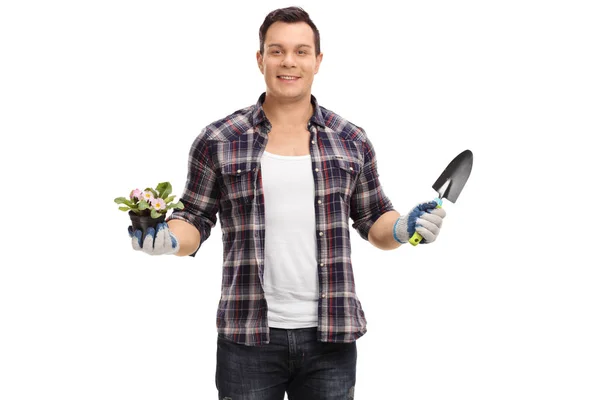 Gardener holding a flower in a pot and a spade — Stock Photo, Image