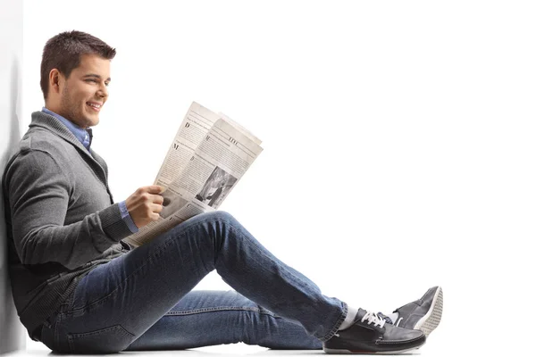 Sentado en el suelo leyendo un periódico — Foto de Stock