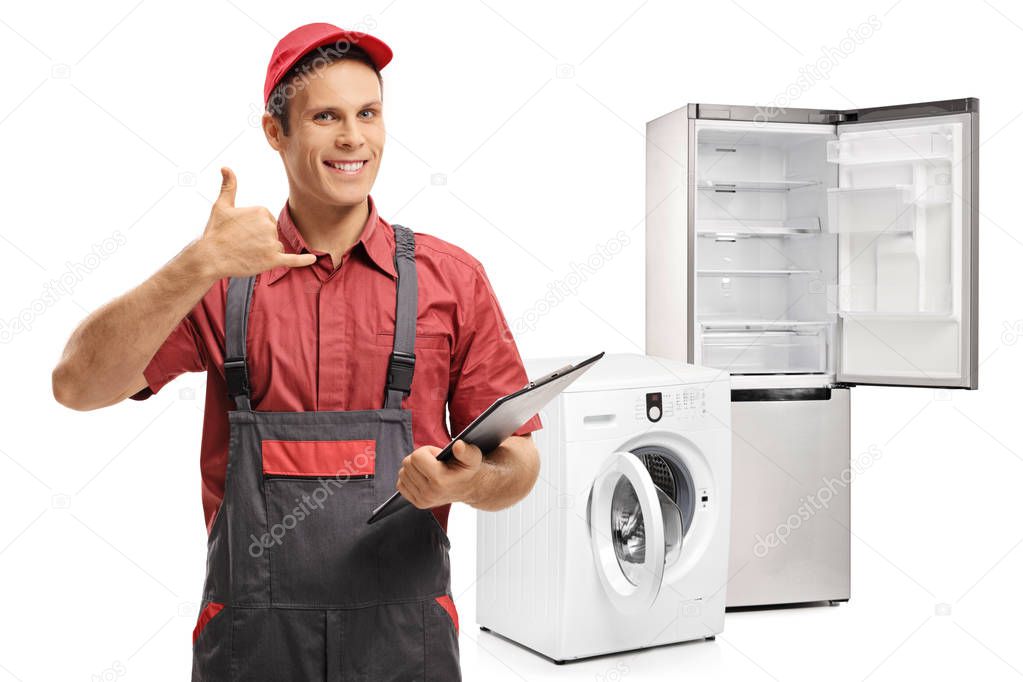 Repairman making a call me gesture in front of a washing machine and a fridge