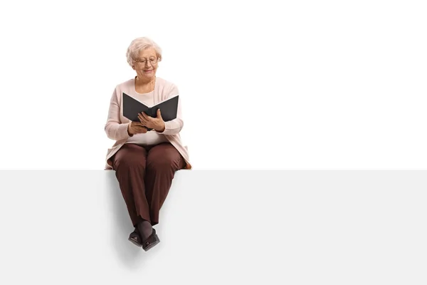 Mulher sentada em um painel e lendo um livro — Fotografia de Stock