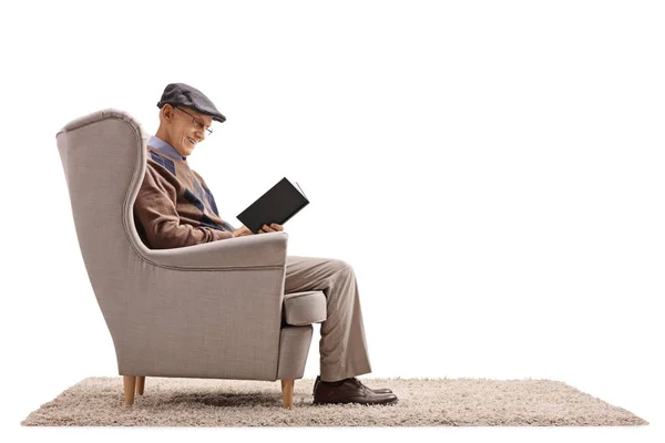 Homem sentado em uma poltrona lendo um livro — Fotografia de Stock
