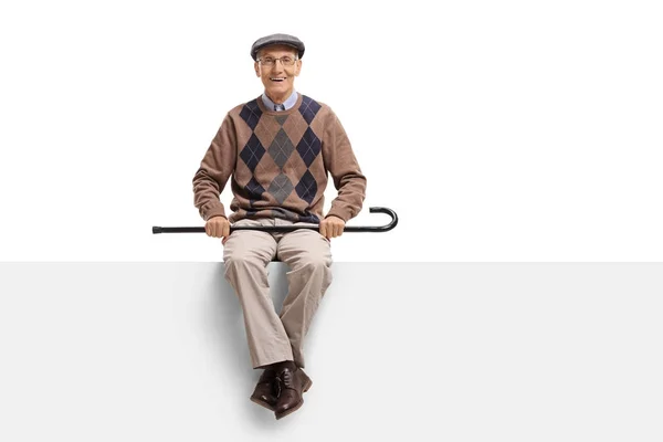 Пожилой человек с тростью, сидящий на панели — стоковое фото