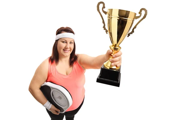 Overweight woman with a weight scale and a trophy — Stock Photo, Image