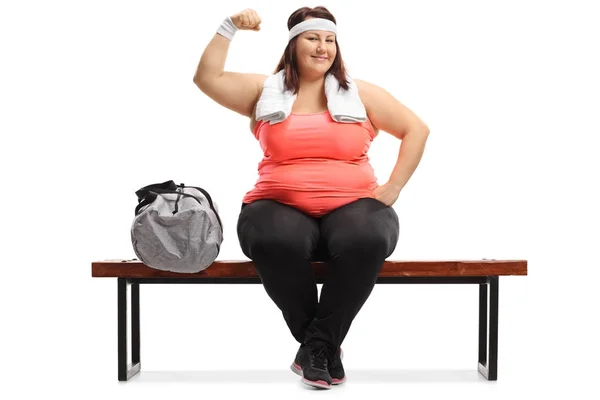 Femme assise sur un banc et fléchissant ses biceps — Photo