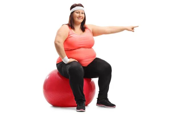 Mulher sentada em uma bola pilates e apontando — Fotografia de Stock