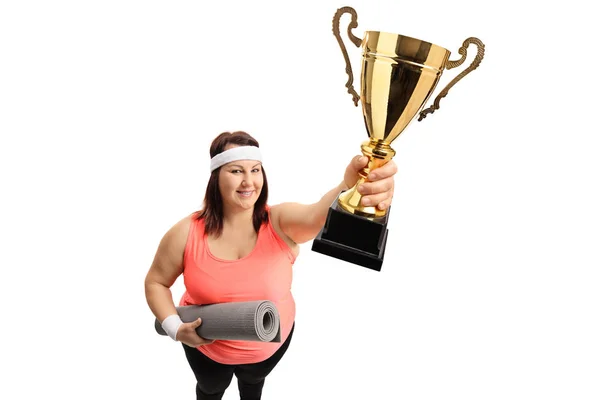 Femme en surpoids avec un tapis d'exercice et un trophée — Photo