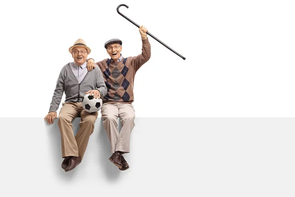 Personas mayores alegres con un balón de fútbol sentado en un panel —  Fotos de Stock