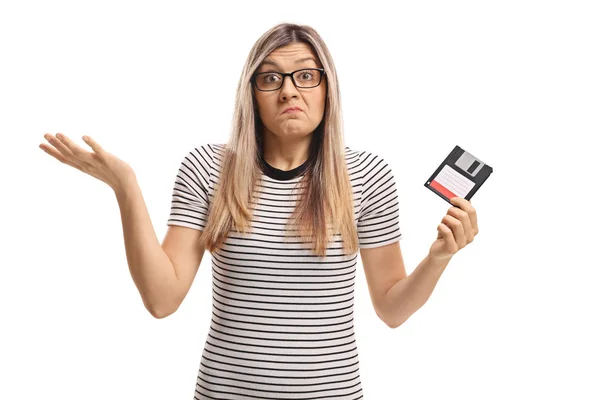 भ्रमित महिला एक फ्लॉपी डिस्क पकड़े हुए — स्टॉक फ़ोटो, इमेज