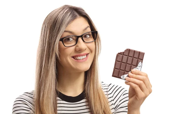 Женщина держит кусочек шоколада и улыбается — стоковое фото