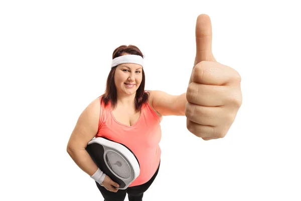 Donna con una scala di peso che fa un gesto pollice in su — Foto Stock