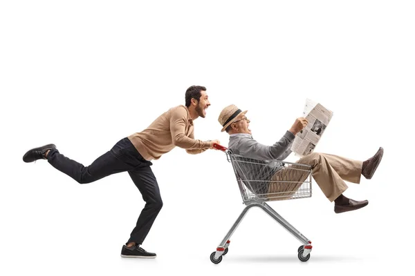 Hombre montando dentro de un carrito de compras siendo empujado por un hombre — Foto de Stock