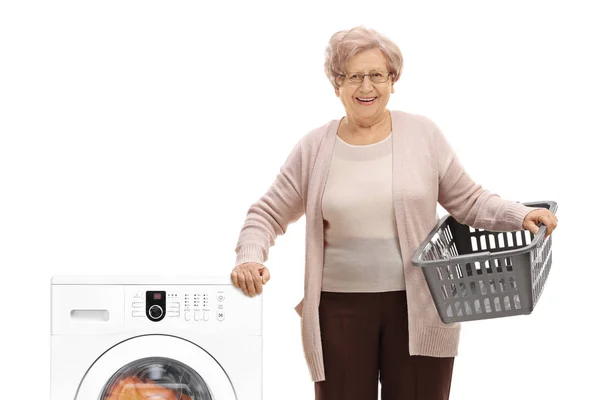 Жінка з кошиком для білизни біля пральної машинки — стокове фото