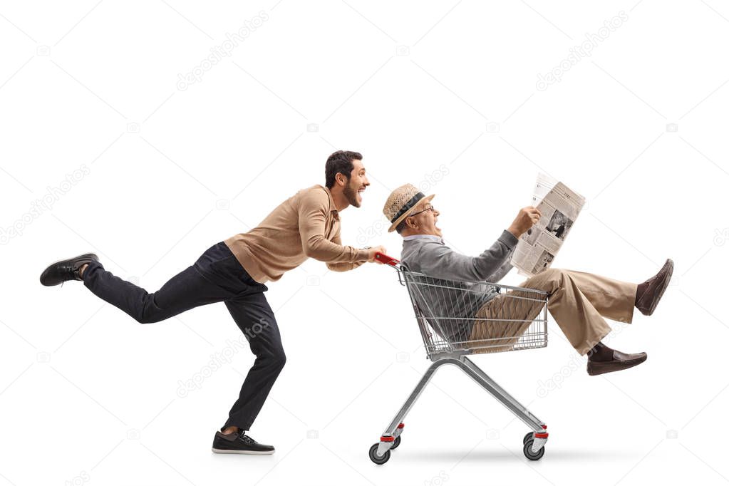 man riding inside a shopping cart being pushed by a man 