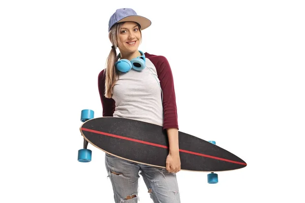 Θηλυκό σκέιτερ με ένα longboard και ακουστικά χαμογελώντας — Φωτογραφία Αρχείου