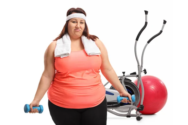 Mulher exercitando-se com halteres na frente de equipamento de exercício — Fotografia de Stock