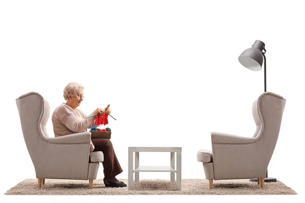 Vrouw zitten in een leunstoel en breien — Stockfoto