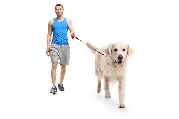 Ung man i sportkläder promenader en hund — Stockfoto