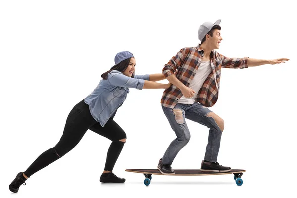 Teenager-Mädchen schubst einen Teenager-Jungen auf einem Longboard — Stockfoto