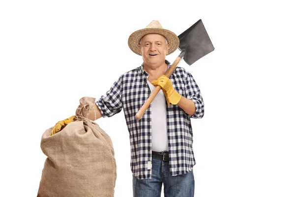 Boer hoding een jute zak en een schop — Stockfoto