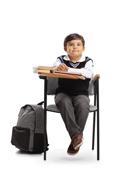 Маленький школьник, сидящий в школьном кресле — стоковое фото