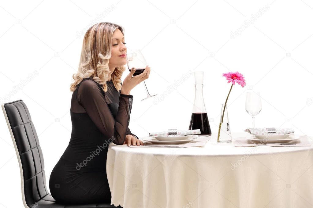 woman smelling a glass of wine at a restaurant table