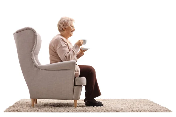 Elderly woman with a cup seated in an armchair — Stock Photo, Image