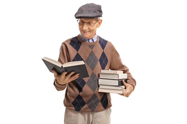 Oudere man met een stapel boeken lezen — Stockfoto