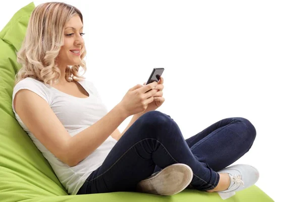 Mujer sentada en una bolsa de frijoles usando un teléfono — Foto de Stock