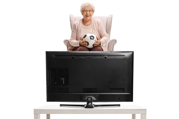 Kadın bir koltuk ve televizyonda futbol izlerken — Stok fotoğraf