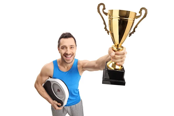 Guy holding een gewicht-schaal en een gouden trofee ik — Stockfoto