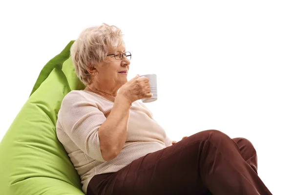 Mujer mayor con una taza sentada en una bolsa de frijoles — Foto de Stock