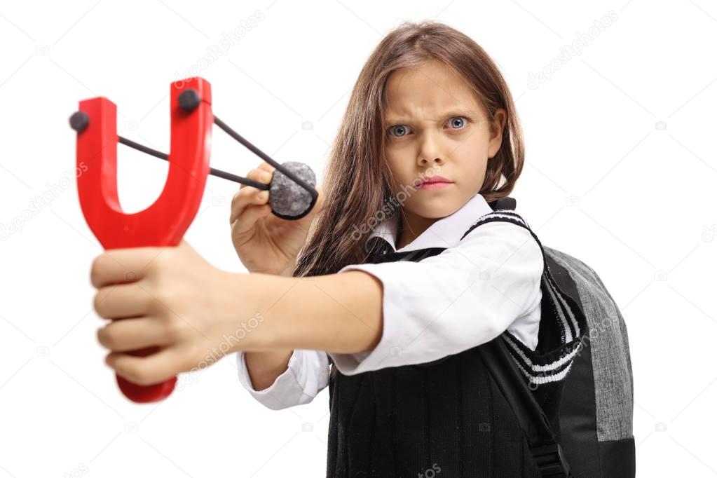 Angry schoolgirl aiming with a stone and a slingshot