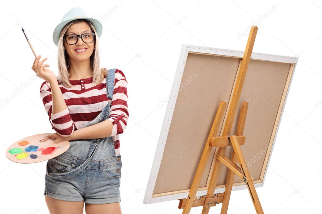 woman with a paintbrush and a color palette next to an easel