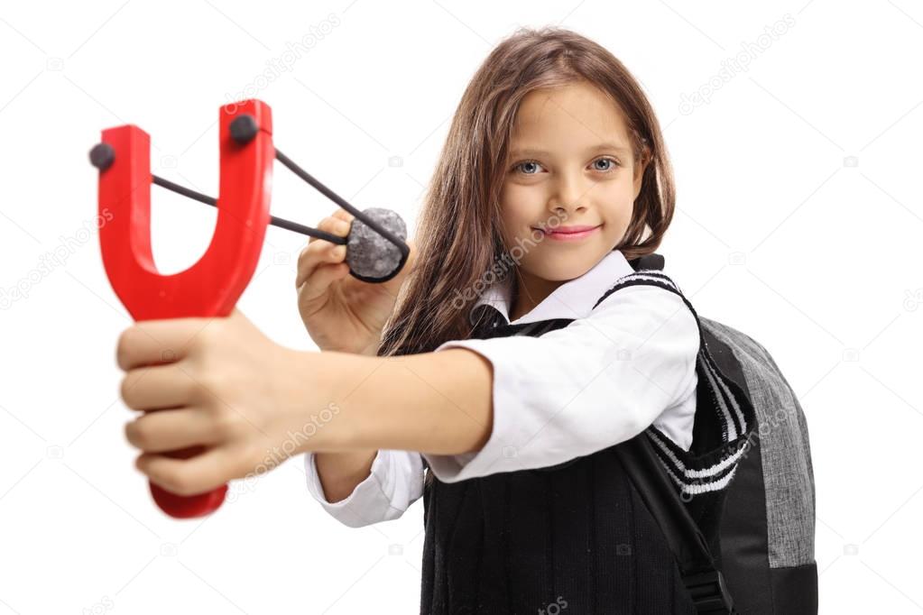schoolgirl aiming with a slingshot and a stone and smiling