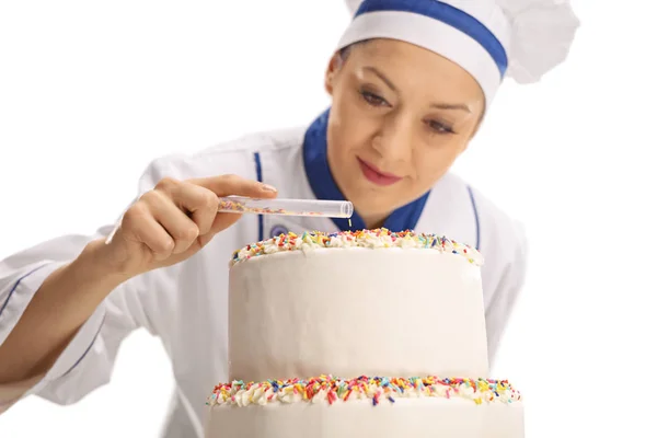 Chef hembra poniendo aspersiones en un pastel — Foto de Stock