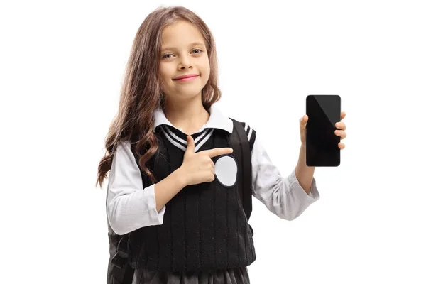 Liten skolflicka hålla en telefon och pekar — Stockfoto