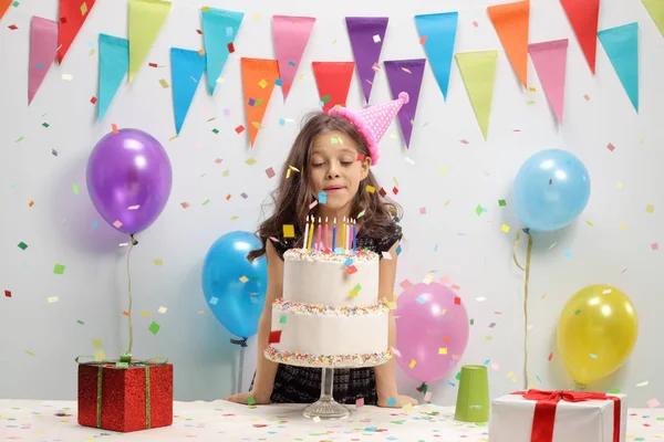 Девушка задувает свечи на торте на день рождения — стоковое фото