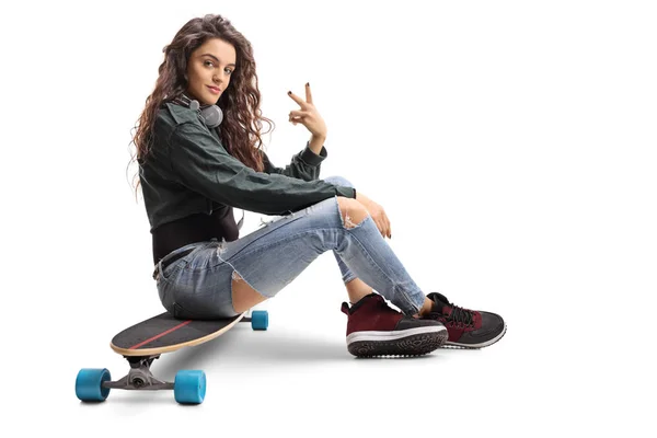 Meisje zittend op een longboard en een vrede gebaar maken — Stockfoto