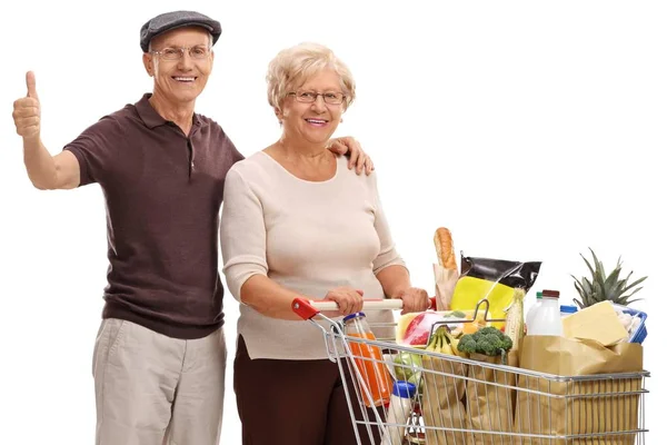 Pareja con un carrito de compras haciendo un gesto de pulgar hacia arriba — Foto de Stock