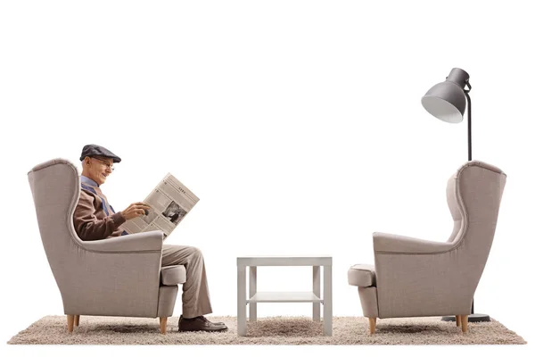 Senior sentado en un sillón y leyendo un periódico — Foto de Stock