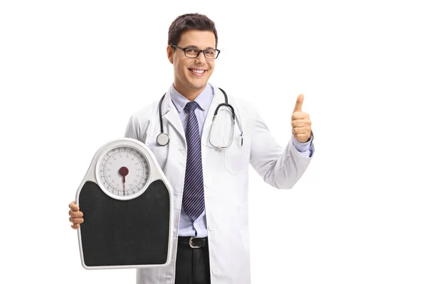 Médico segurando uma balança de peso e fazendo um gesto de polegar para cima — Fotografia de Stock