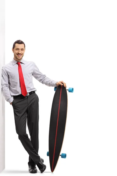 Zakenman met een longboard leunend tegen een muur — Stockfoto