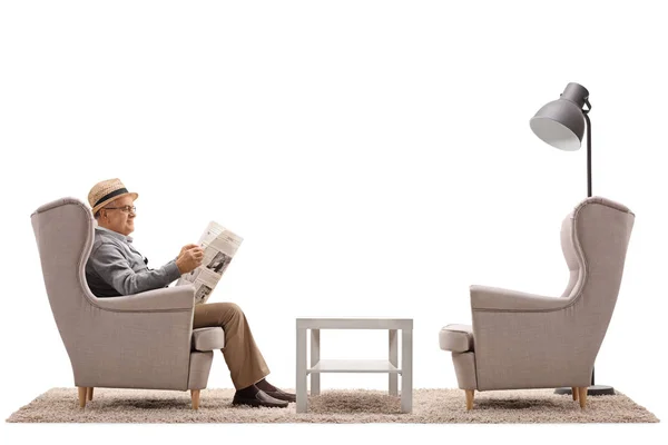 Man seated in an armchair reading a newspaper — Stock Photo, Image