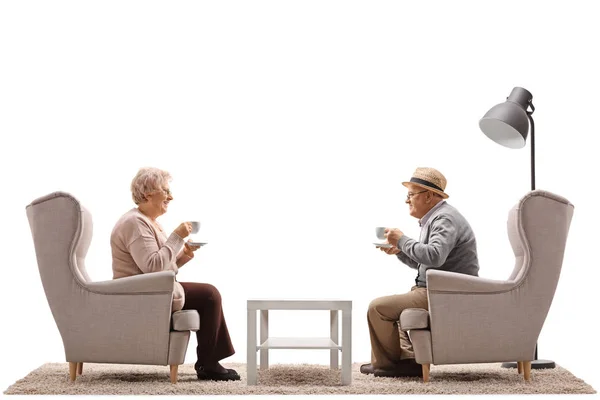 Woman and man with cups sitting in armchairs — Stock Photo, Image