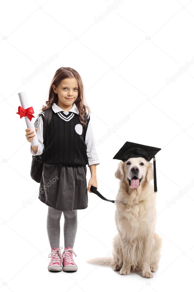 Full length portrait of a little schoolgirl with a diploma and a dog wearing a graduation hat isolated on white background