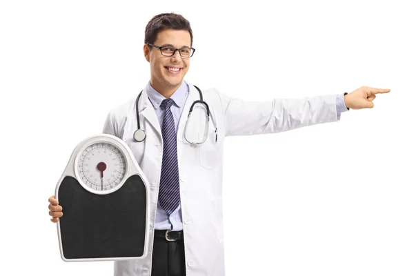 Doctor holding a weight scale and pointing — Stock Photo, Image