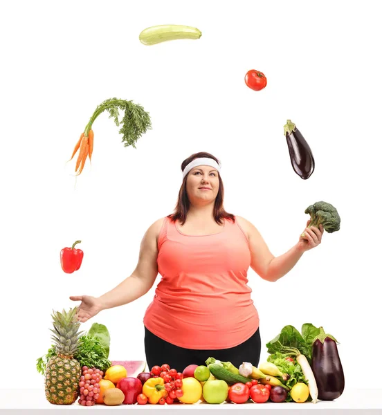 Übergewichtige Frau Jongliert Hinter Einem Tisch Mit Obst Und Gemüse — Stockfoto