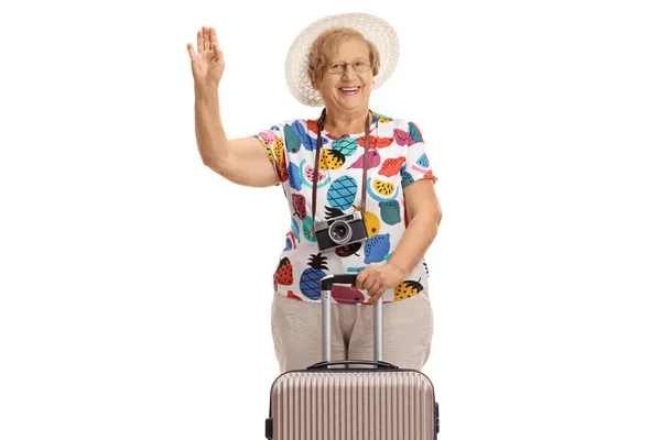 Туристка с чемоданом машет и улыбается — стоковое фото