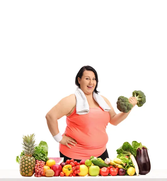 タオルとブロッコリー ダンベルの果物や野菜は 白い背景で隔離のテーブルの後ろの肥満女性 — ストック写真